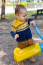 Cute baby boy having fun on outdoor playground. Toddler activities. Serious baby swinging on swing Royalty Free Stock Photo