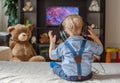 Cute baby boy with headphones watching TV sitting on a couch in the living room at home Royalty Free Stock Photo