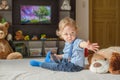Cute baby boy and his dog plush toy watching TV sitting on a couch in the living room at home Royalty Free Stock Photo
