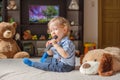 Cute baby boy and his dog plush toy watching TV sitting on a couch in the living room at home Royalty Free Stock Photo