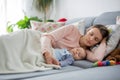 Cute baby boy and his mother, lying on the couch in living room Royalty Free Stock Photo