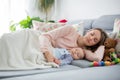 Cute baby boy and his mother, lying on the couch in living room Royalty Free Stock Photo
