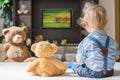 Cute baby boy and his teddy bear watching TV sitting on a couch in the living room at home Royalty Free Stock Photo