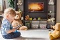 Cute baby boy and his teddy bear watching TV sitting on a couch in the living room at home Royalty Free Stock Photo