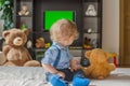 Cute baby boy and his teddy bear watching TV sitting on a couch in the living room at home Royalty Free Stock Photo