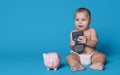 Cute baby boy holding calculator and piggybank