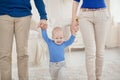 Cute baby boy holding father and mother by the hand and takes first steps Royalty Free Stock Photo