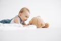 Cute baby boy lies on floor and plays with toy plush bear Royalty Free Stock Photo
