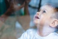 Cute baby boy looking in the window glass. Loneliness of children and waiting for kindness. Orphanage and orphans Royalty Free Stock Photo