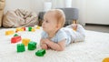 Cute baby boy lying on carpet among colorful toy bricks and blocks Royalty Free Stock Photo