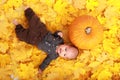 Baby boy lying by pumpkin on maple leaves Royalty Free Stock Photo