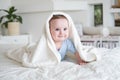 Cute baby boy 6 months old in blu bodysuit smiling and lying on bed with white plaid at home Royalty Free Stock Photo