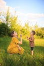 Cute baby boy and mother blowing on a dandelions on green lawn. Summertime photography for ad or blog about motherhood Royalty Free Stock Photo