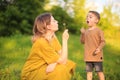 Cute baby boy and mother blowing on a dandelions on green lawn. Summertime photography for ad or blog about motherhood Royalty Free Stock Photo