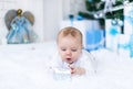 Cute baby boy playing with christmas gift in white room. Royalty Free Stock Photo