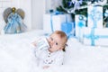 Cute baby boy playing with christmas gift in white room. Royalty Free Stock Photo