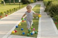 Cute baby boy playing with colorful balls in green grass in the garden, park or backyard Royalty Free Stock Photo