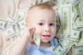 Cute baby boy playing with a lot of money like talking on telephone, american hundred dollars cash Royalty Free Stock Photo
