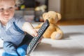 Cute baby boy playing with the remote control on a couch in the living room at home Royalty Free Stock Photo