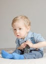 Cute baby boy playing with the remote control to watch TV sitting on a couch, at home Royalty Free Stock Photo