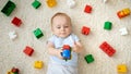 Cute baby boy playing toy car on carpet next to heap of colroful toys, blocks and bricks. Concept of children Royalty Free Stock Photo