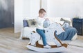 Cute baby boy riding wooden traditional rocking horse toy in white bedroom. Child playing in nursery room. Royalty Free Stock Photo