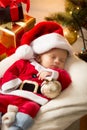 Cute baby boy in Santa costume sleeping ext to Christmas gifts Royalty Free Stock Photo