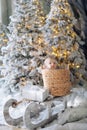 Cute baby boy sits inside of wicker basket on sled among artificial snow and Christmas trees Royalty Free Stock Photo