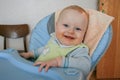 Cute baby boy sitting on the baby chair and waiting dinner.