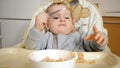 Cute baby boy sitting in highchair playing with food and making mess. Concept of parenting, healthy nutrition and baby feeding Royalty Free Stock Photo