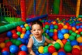 Cute baby boy sitting in a pile of colorful plastic balls Royalty Free Stock Photo