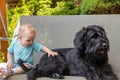 Cute baby boy is sitting on a swing next to black dog Royalty Free Stock Photo