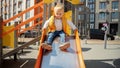 Cute baby boy sitting on the top of slide and riding down. Happy parenting, family having time together, kids and parents outdoors Royalty Free Stock Photo