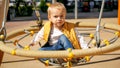 Cute baby boy swinging in round nest swing at park. Children playing outdoor, kids outside, summer holiday and vacation Royalty Free Stock Photo