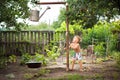 Cute baby boy taking water procedures in summer garden. Outdoor baby bathing. Funny little boy playing with garden hose in sunny b Royalty Free Stock Photo