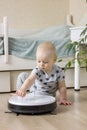 Cute baby boy toddler pushing the button on white robotic vacuum cleaner. Royalty Free Stock Photo