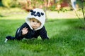 Cute baby boy wearing a Panda bear suit sitting in grass at park. Royalty Free Stock Photo