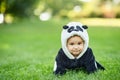 Cute baby boy wearing a Panda bear suit sitting in grass at park. Royalty Free Stock Photo