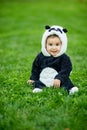 Cute baby boy wearing a Panda bear suit sitting in grass at park. Royalty Free Stock Photo