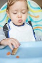 Cute baby child eating by itself and not liking the food