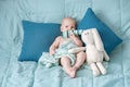 Cute baby closed mouth with hare toy ear on bed. Portrait of a child with emotions Royalty Free Stock Photo