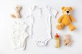 Cute baby clothes for boy and girl, rattle, bottle and dummy space in the middle, on white background top view. AI Royalty Free Stock Photo