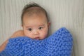 Cute baby covered in blue towel quilt making various expressions