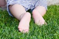 Cute baby crawling on green grass. Rear view. Primary focus on baby feet. Royalty Free Stock Photo