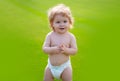 Cute baby in diaper on green grass in summertime. Funny little kid on nature. Happy Childhood. Baby and summer sunny