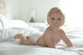 Cute baby in diaper with pacifier lying on bed at home Royalty Free Stock Photo