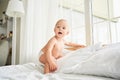 A cute baby in a diaper takes the first steps in bed Royalty Free Stock Photo