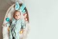 Cute baby Easter bunny. Little baby boy with bunny ears and Easter eggs in wicker basket in white fur. Symbol of Easter holiday, Royalty Free Stock Photo