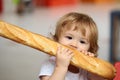 Cute baby eating French baguette white bread. Funny toddler child eating sandwich, self feeding concept.