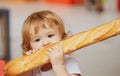 Cute baby eating French baguette white bread. Funny toddler child eating sandwich, self feeding concept. Royalty Free Stock Photo